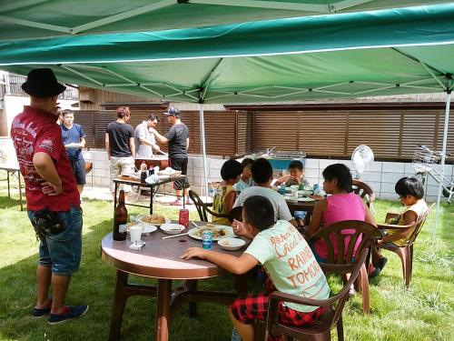 a group of people sitting at tables under a tent at Minshuku Osaki in Nishio