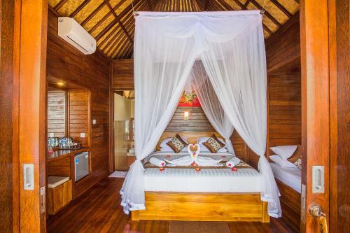 a bedroom with a bed with a canopy at Tatak Bunut Private Villa in Nusa Lembongan