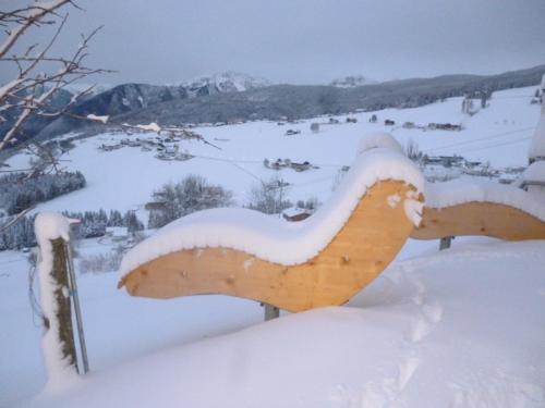 a bench covered in snow on a mountain at Pitznerhof in Maranza