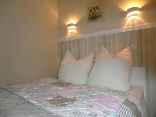 a bedroom with a bed with white pillows and two lights at Ferienwohnung Rosenflair in Schönebeck