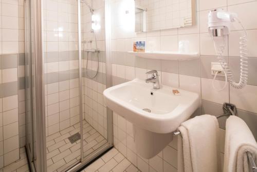 a white bathroom with a sink and a shower at Hotel Lands End in Den Helder