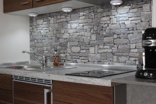 eine Küche mit einem Waschbecken und einer Steinmauer in der Unterkunft Appartement in Sankt Englmar mit KlimaWärmetauscher in Sankt Englmar