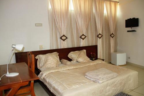 ein Schlafzimmer mit einem Bett mit einem Tisch und einer Lampe in der Unterkunft Amazing Grace Residence in Cotonou