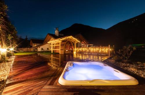 bañera de hidromasaje en una terraza de madera por la noche en Gitschberg - Appartements, en Vandoies