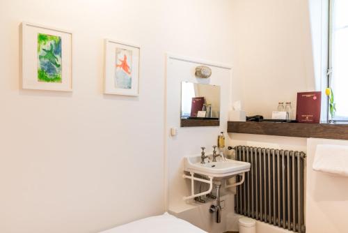 a white bathroom with a sink and a radiator at Hotel Beau Séjour Lucerne in Luzern