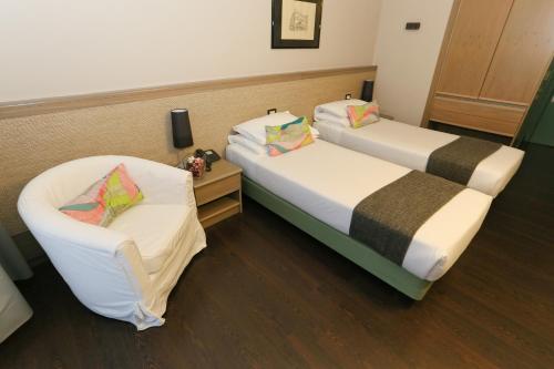 two beds and a chair in a room at Hotel Forum in SantʼIlario dʼEnza