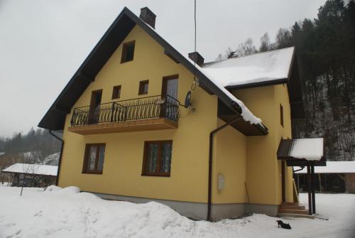 ein gelbes Haus mit Balkon im Schnee in der Unterkunft Kwatery prywatne Agnieszka i Paweł Kuźlak in Wierchomla Wielka