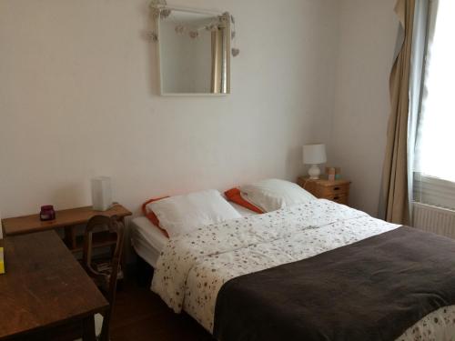 a bedroom with a bed and a table and a mirror at Appartement 4 personnes centre ville in Châteauneuf-sur-Loire