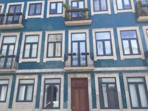 een blauw gebouw met witte ramen en een deur bij OHH -Porto 4 you- Deluxe Apartment With Free Parking in Porto
