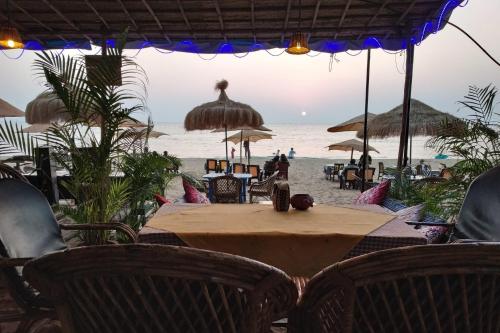 a table and chairs on a beach with the ocean at Sea Front Beach Huts in Patnem