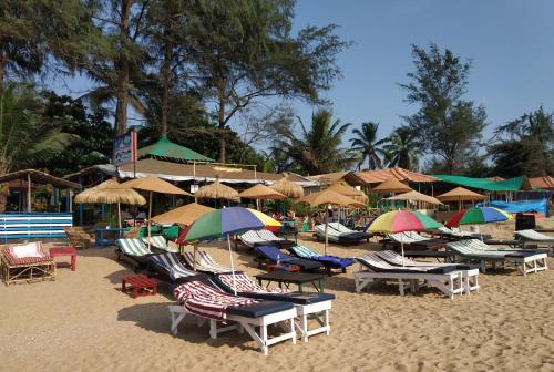 a group of chairs and umbrellas on a beach at Sea Front Beach Huts in Patnem