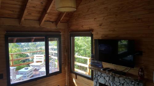 a living room with a tv and two windows at Pendientes de Moquehue in Moquehue