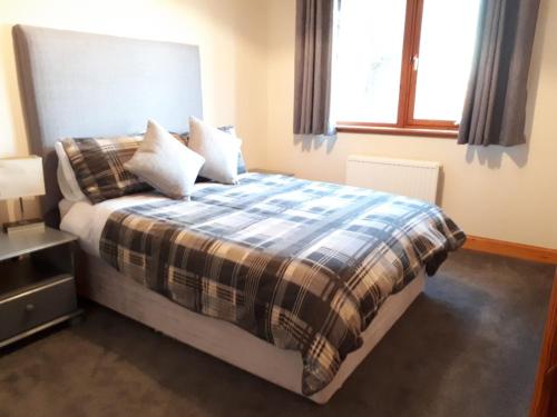 a bedroom with a bed with a blanket and pillows at Breadalbane Suites in Wick
