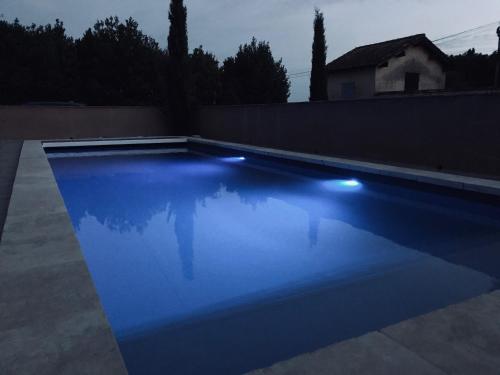 a swimming pool with blue lighting in a backyard at Mas Guiraud, le Coquet in Beaucaire