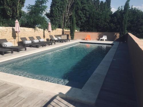 a swimming pool with chaise lounges and chairs next to it at Mas Guiraud, le Coquet in Beaucaire
