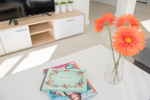 a table with a vase with flowers and a book at El Mirador De Villamartin - La Zenia & Golf in Playas de Orihuela
