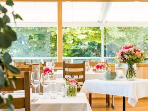 a dining room with tables with flowers on them at Landgasthof Hotel Menzberg in Menzberg
