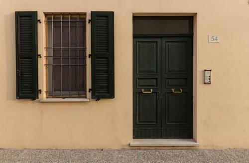- un bâtiment avec une porte verte et 2 fenêtres dans l'établissement La Rosa, à Ferrare