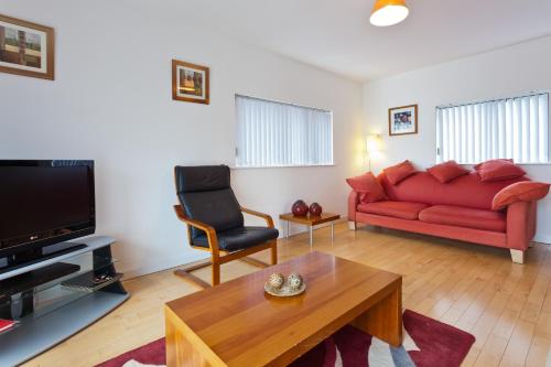 a living room with a red couch and a table at 6a Cedar Grove in Bangor