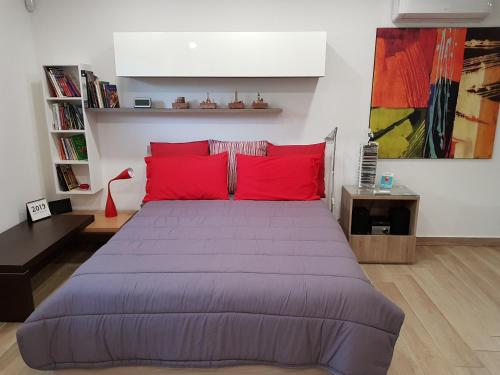 a bedroom with a large bed with red pillows at Folco Studio Apartment in Piazza Armerina