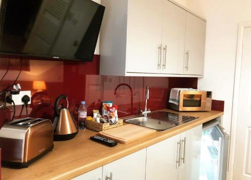 a kitchen counter with a microwave and a sink at Bede Apartments in Coventry