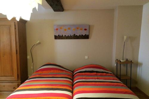 ベーブレンハイムにあるGite de la Vieille Forgeのカラフルなストライプ枕付きのベッド1台