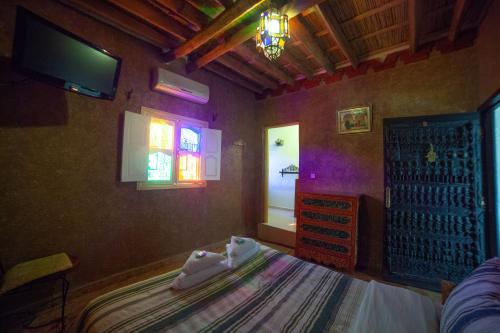 - une chambre avec un lit, une fenêtre et une télévision dans l'établissement Hotel Rochers Peints, à Tafraout