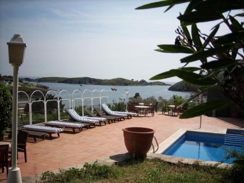 un patio con sillas y una piscina y vistas al agua en Bungalow Hotel Port-Lligat, en Cadaqués