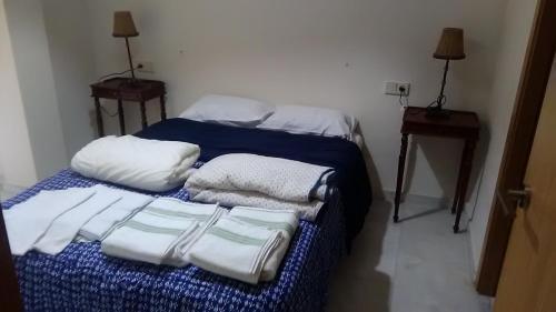 1 cama con 3 almohadas y toallas en Apartamento en el centro de Huelva, en Huelva
