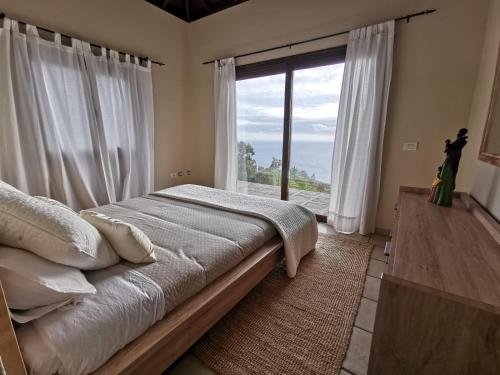 sypialnia z łóżkiem i dużym oknem w obiekcie My hell Village w mieście Tijarafe