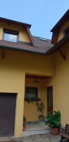 a yellow house with potted plants in front of it at Chalupa U Zvonka Trojanovice in Frenštát pod Radhoštěm