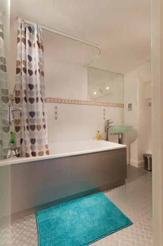 a bathroom with a tub and a mirror and a rug at Lace Market Apartments - City Centre - 4 Beds Apartment with 2 Bathrooms and full Kitchen in George Street - close to Victoria Centre Shopping Centre - Parking for Cars & Vans from Five Pounds a Day - Sunday 1pm Check-out in Nottingham