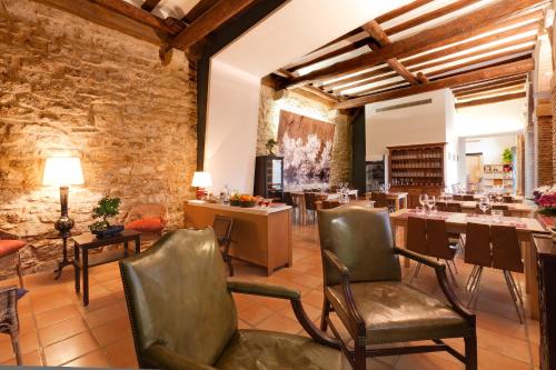 a restaurant with chairs and tables and a stone wall at Hospedería de Alesves in Villafranca