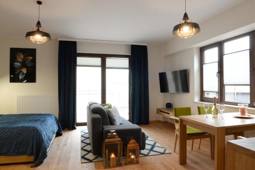a bedroom with a bed and a living room at Apartamenty Kora in Krynica Zdrój
