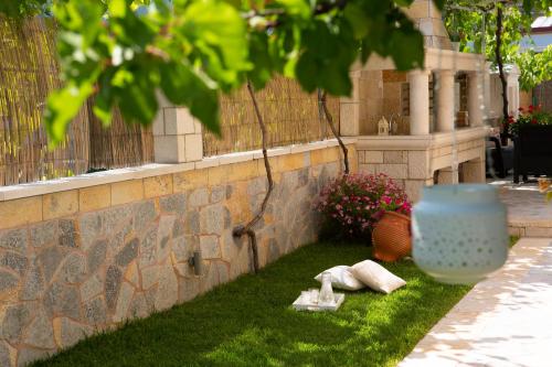 a brick wall with a blue vase on the grass at Adria Luxury Apartments in Nydri