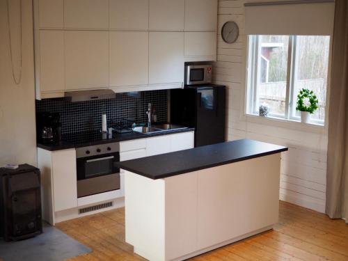 une cuisine avec des placards blancs et un comptoir noir dans l'établissement Orsastuguthyrning-Slättberg, à Orsa