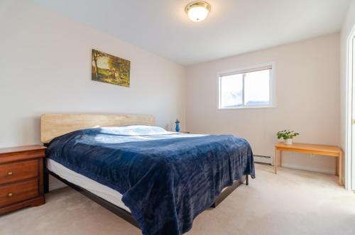 a bedroom with a bed with a blue blanket on it at 3 Private, spacious, bright rooms in a Gorgeous house in New Westminster