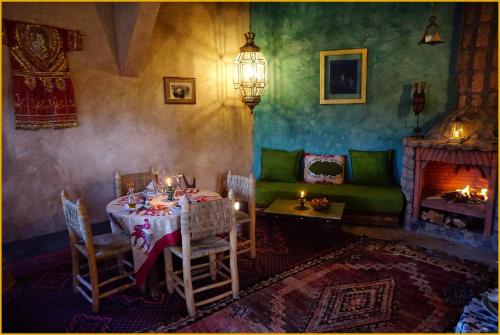 a dining room with a table and a fireplace at Lodge Hara Oasis in Agdz