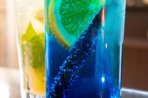 a blue glass with a lemon and a drink at Hotel Paryski Art & Business Zakopane - Basen Jacuzzi Sauna Małpi Gaj in Zakopane