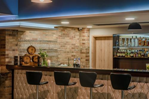 a bar with black chairs and a brick wall at Hotel Paryski Art & Business Zakopane - Basen Jacuzzi Sauna Małpi Gaj in Zakopane