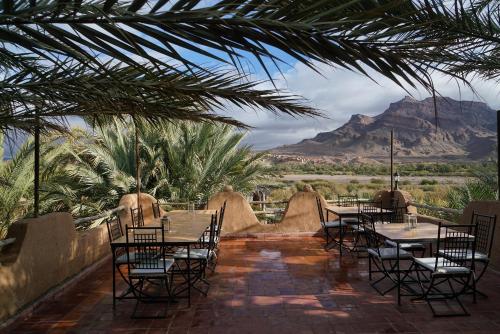 a patio with tables and chairs with mountains in the background at Lodge Hara Oasis in Agdz