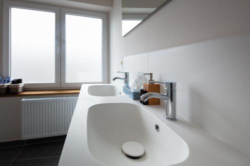 een badkamer met een witte wastafel en 2 ramen bij Big Baron in Brugge