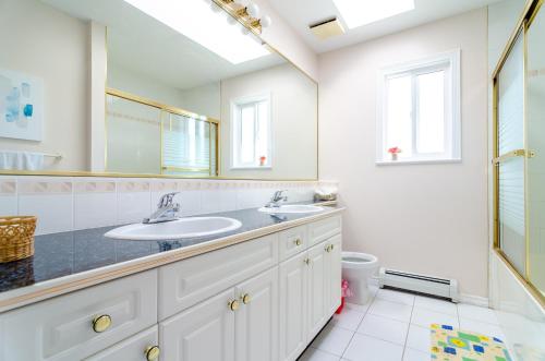 y baño con lavabo, espejo y aseo. en 3 Private, spacious, bright rooms in a Gorgeous house, en New Westminster