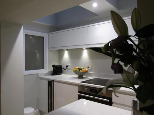 a kitchen with white cabinets and a bowl of fruit on the counter at The Apartment, Lower Ground Floor, Clarendon Place in Leamington Spa