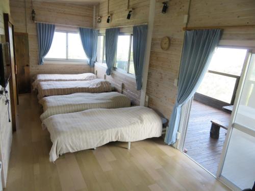 3 camas en una habitación con paredes y ventanas de madera en Okinawa Freedom en Nakijin