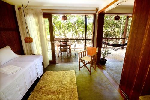 a bedroom with a bed and a balcony with a table at Boa Village- Bungalow Vermelho- Praia de Algodões- Península de Maraú- BA in Marau