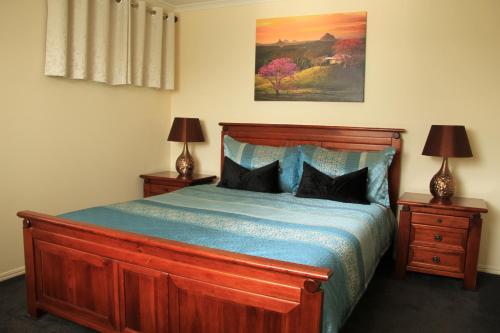um quarto com uma cama de madeira e 2 mesas de cabeceira em "Seasons of Maleny B&B" em Maleny