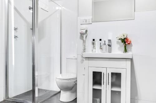 a white bathroom with a toilet and a shower at Airport Hotel Sydney (Formerly Comfort Hotel Sydney Airport) in Sydney
