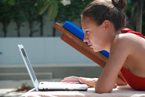 a woman laying on the ground using a laptop computer at The Park Samui in Choeng Mon Beach