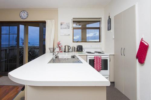 a white kitchen with a sink and a stove at DOLLY KIWI ICONIC BACH IN PRIME LOCATION in New Plymouth